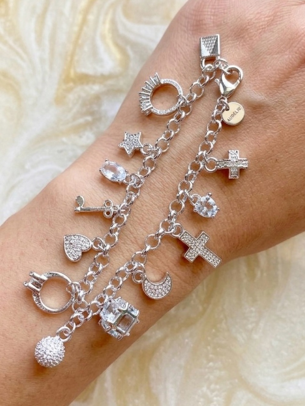 Silver charm bracelet with cross, moon, star, and other charms